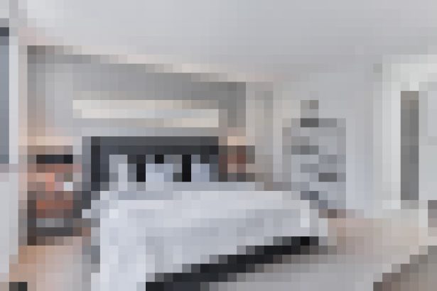 A contemporary bedroom with a neatly made bed, white linens, and a minimal neutral decor.