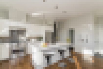 Bright, modern kitchen with white cabinets, a central island, and a wooden floor.