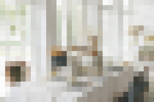 Indoor living space with a person seated near a sofa and coffee table, bright natural light.