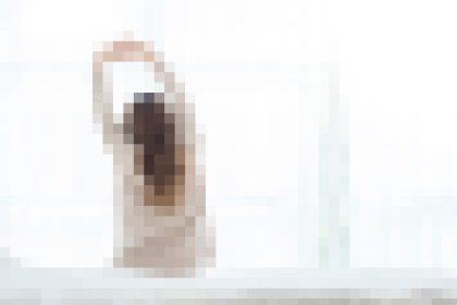 Blurred image of a person with an arm raised against a light background.