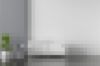 Blurry office scene with a white wall, desk, and a small potted plant on the left side