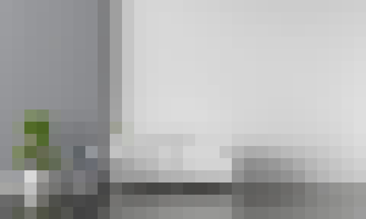 Blurry office scene with a white wall, desk, and a small potted plant on the left side